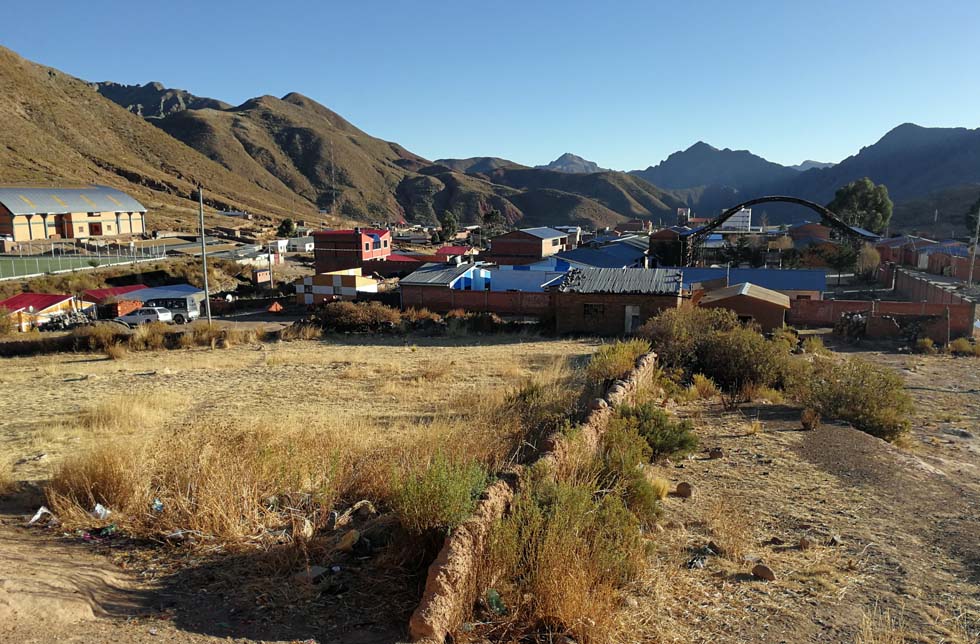 Bolivien: Sicht auf ein Dorf im Anden-Hochland, im Hintergrund ein Sportplatz.