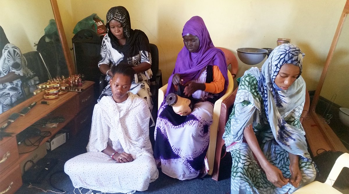 Vier junge Frauen beim Haare knüpfen in einem Coiffeursalon in Mauretanien.