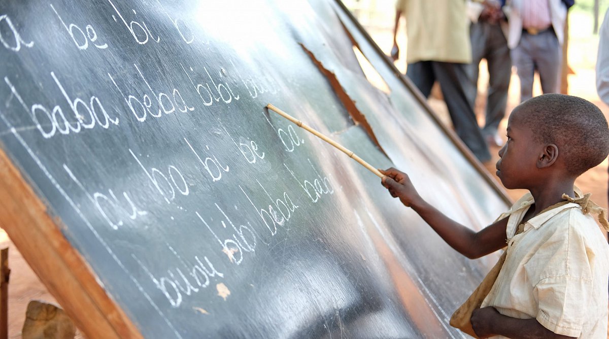 Schüler in Tansania liest von der Wandtafel im Freien