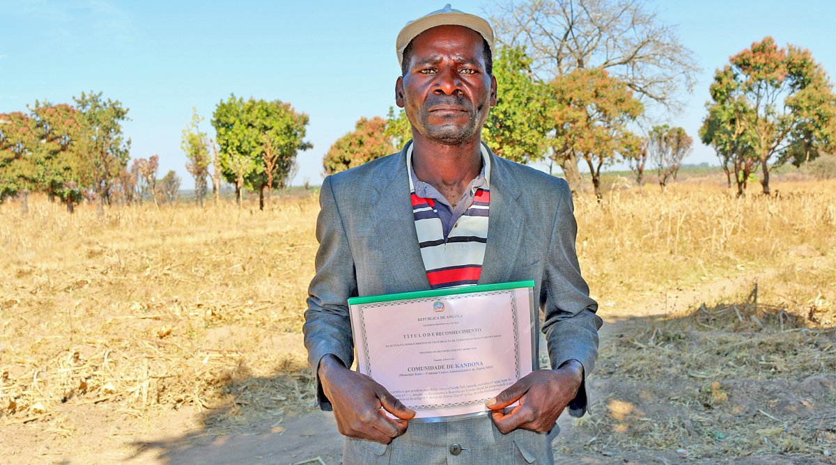 Bauer in Angola hält Grundstückurkunde in der Hand.
