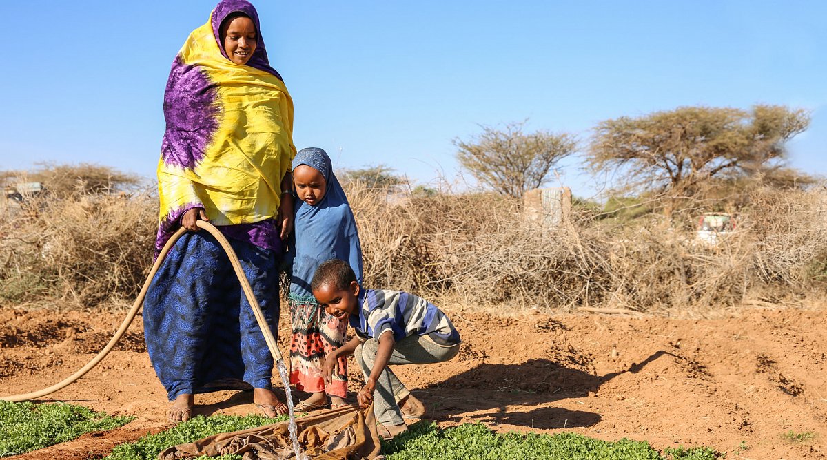 Frau in Somalia mit ihren Kindern an einem Garten