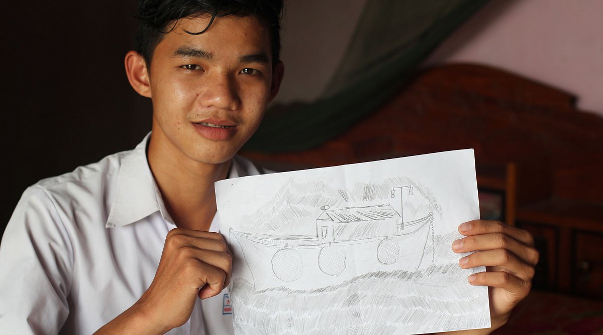 Junge aus Vietnam zeigt ein Bild eines Fischerboots.