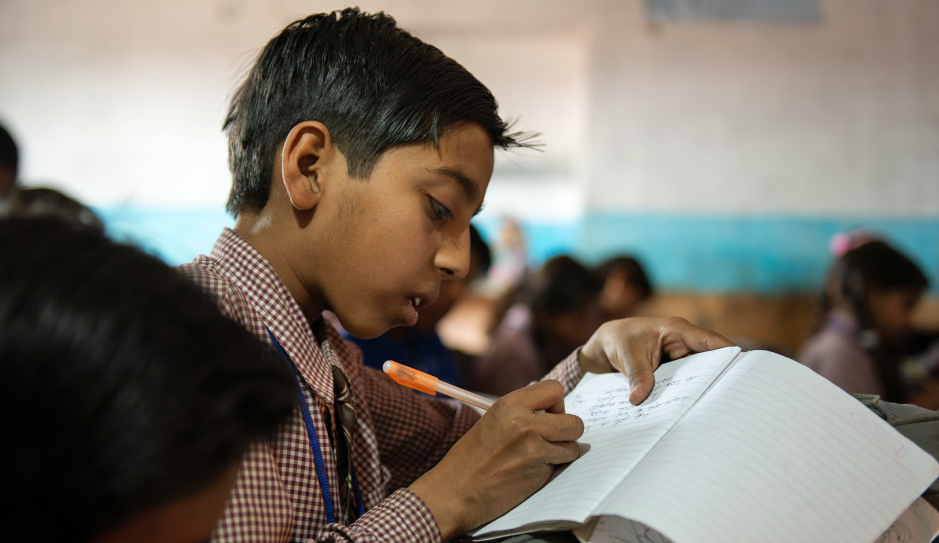 Indien: Ein Junge schreibt in sein Schulheft.