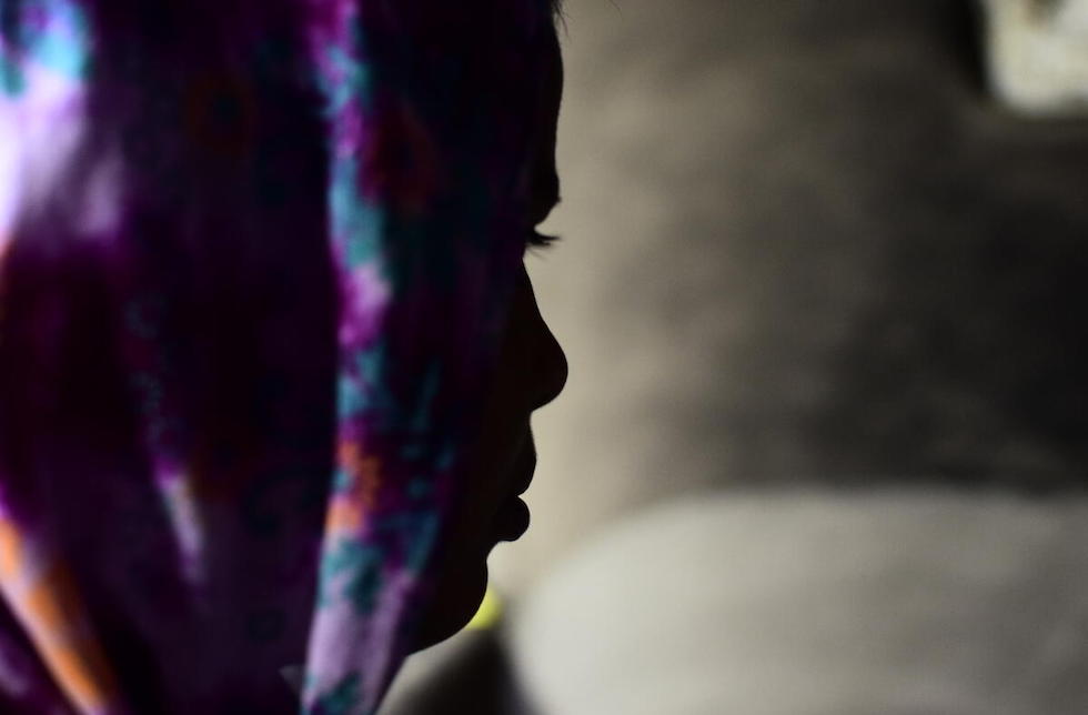  Indien: Das Profil eines Mädchens mit buntem Kopftuch, ihr Gesicht liegt im Schatten.