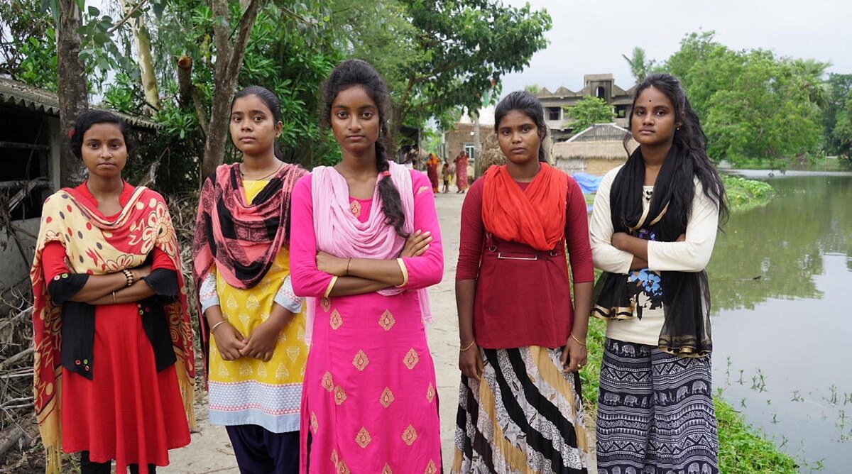 Indien: 5-junge Mädchen in bunten Saris, stehen in einer Reihe, teilweise mit verschränkten Armen und blicken ernst in die Kamera.