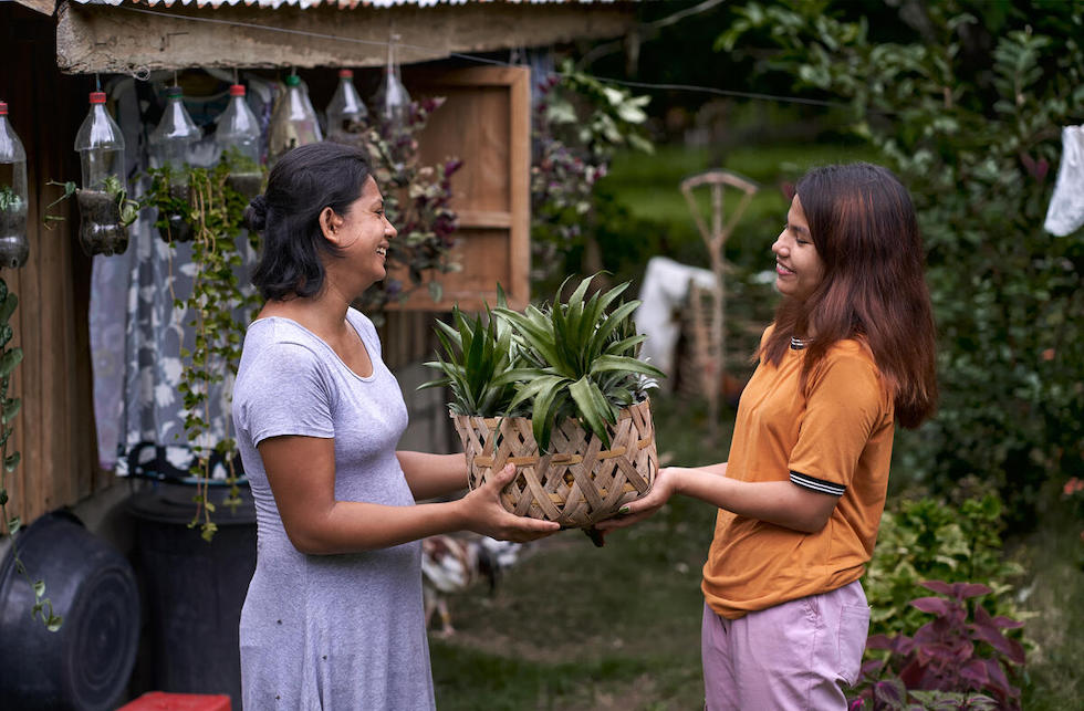 Philippinen: Ein Mädchen überreicht einer Frau einen Korb mit Ananas.