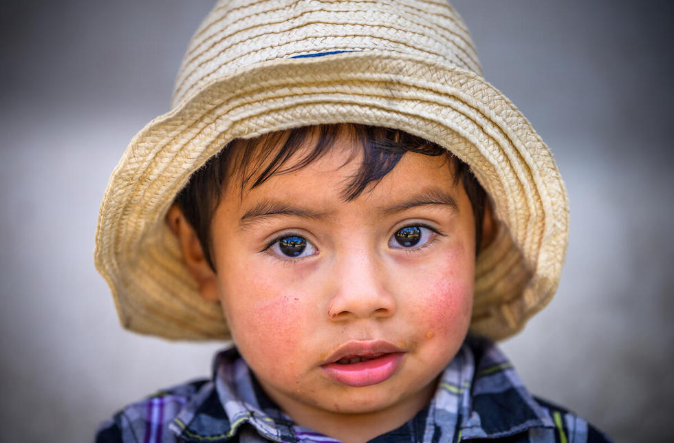 Honduras: Ein kleiner Junge schaut in die Kamera und trägt einen Strohhut.