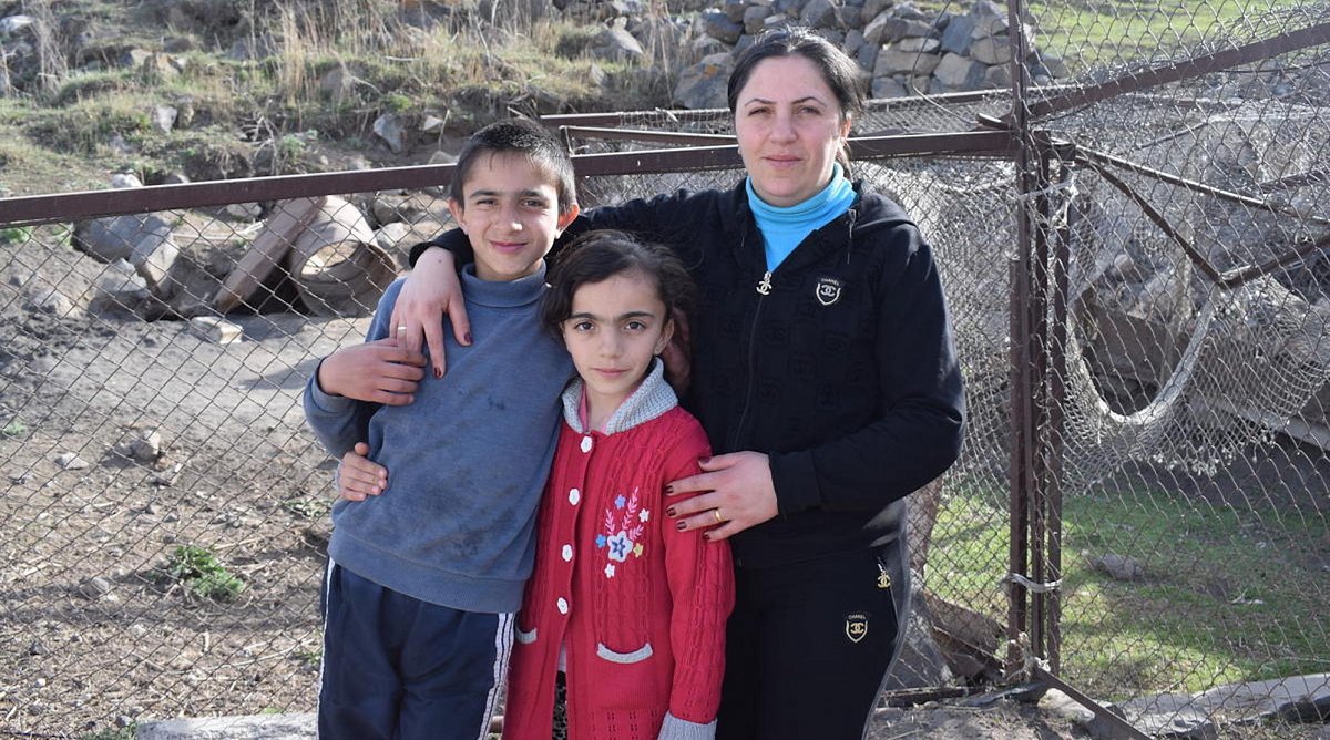 Armenien: Eine Frau und ihre zwei Kinder stehen vor einem Zaun.