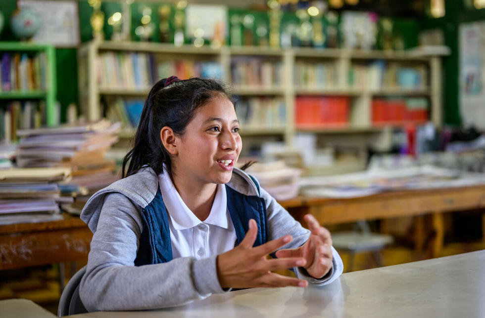 onduras: Ein junges Mädchen sitzt an einem Tisch in der Schulbibliothek.