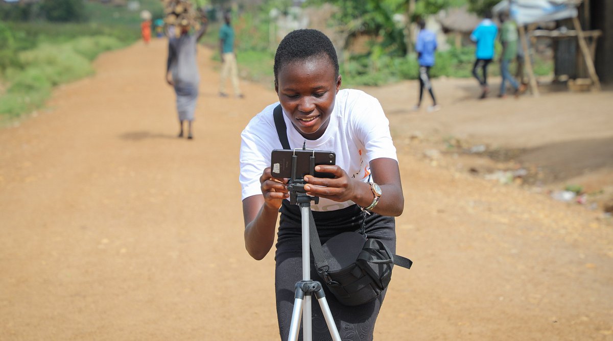 Uganda: Ein Mädchen filmt eine Szene mit ihrem Mobiltelefon.