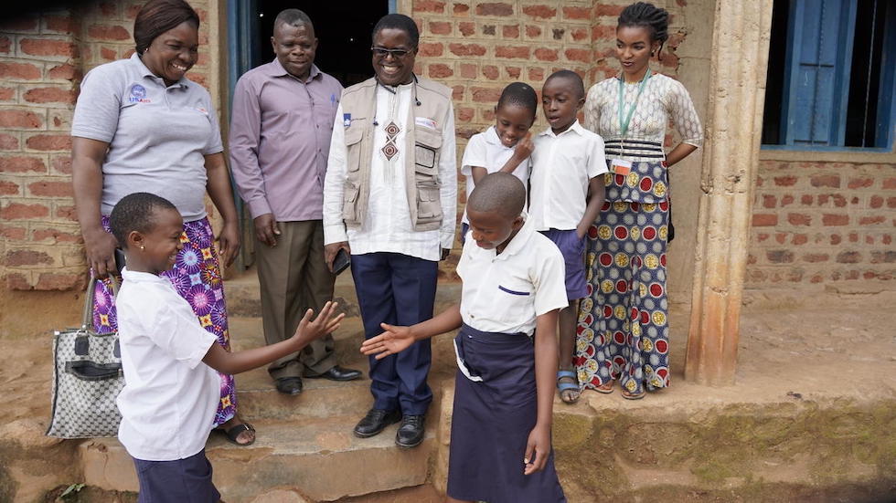 Afrika: Vor einer Menschengruppe geben sich zwei Kinder einen Handschlag.