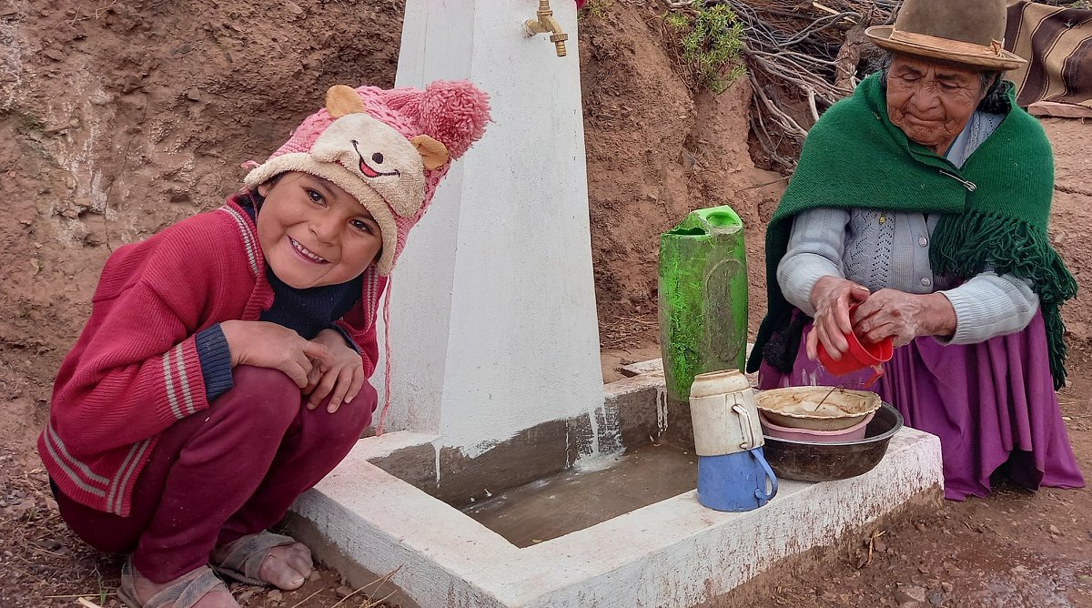 Ein Mädchen und ihre Mutter holen Wasser am neuen Brunnen.