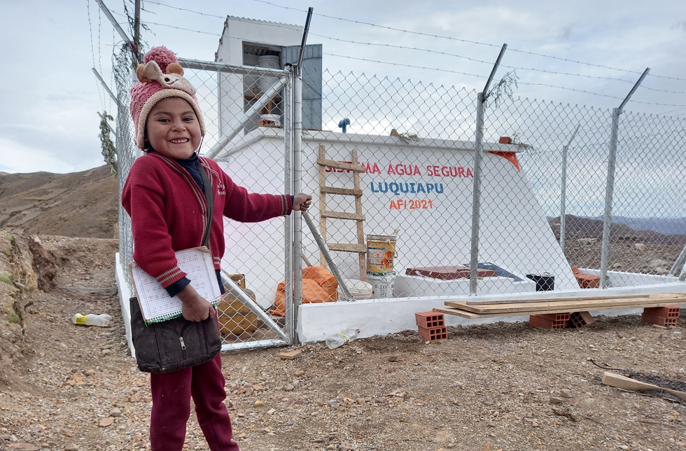 Bolivien: Ein Mädchen zeigt freudestrahlend auf einen neuen Wassertank.
