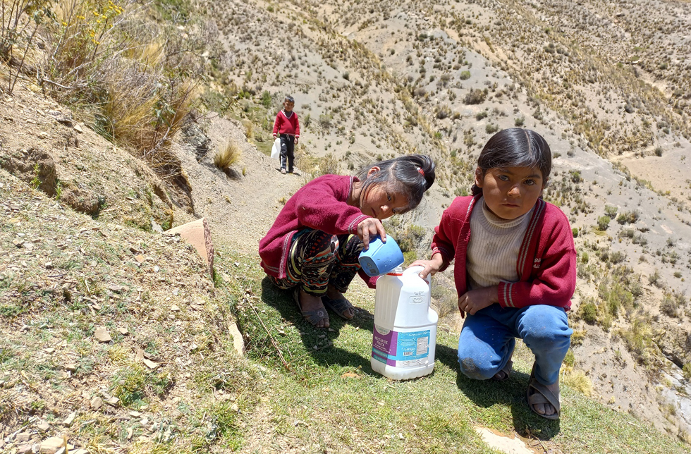 Bolivien: Drei Mädchen mit einer Wasserflasche.)