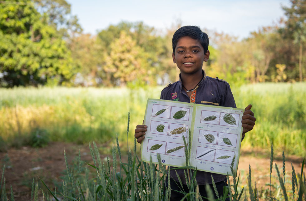 Indien: Ein Junge hält ein Herbarium in den Hände.