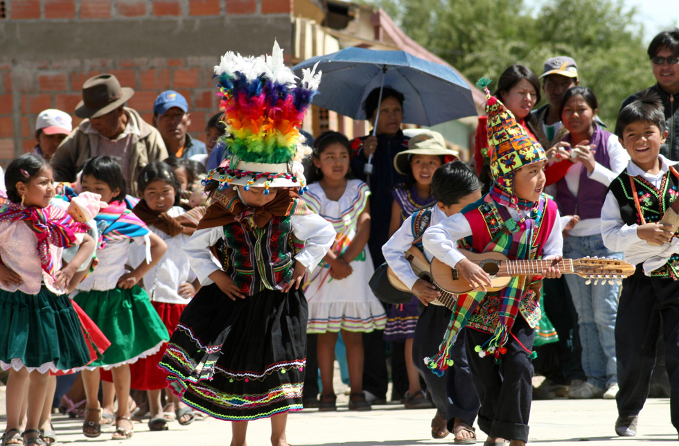 Bolivien: Kinder in traditioneller Tracht tanzen auf der Strasse.)