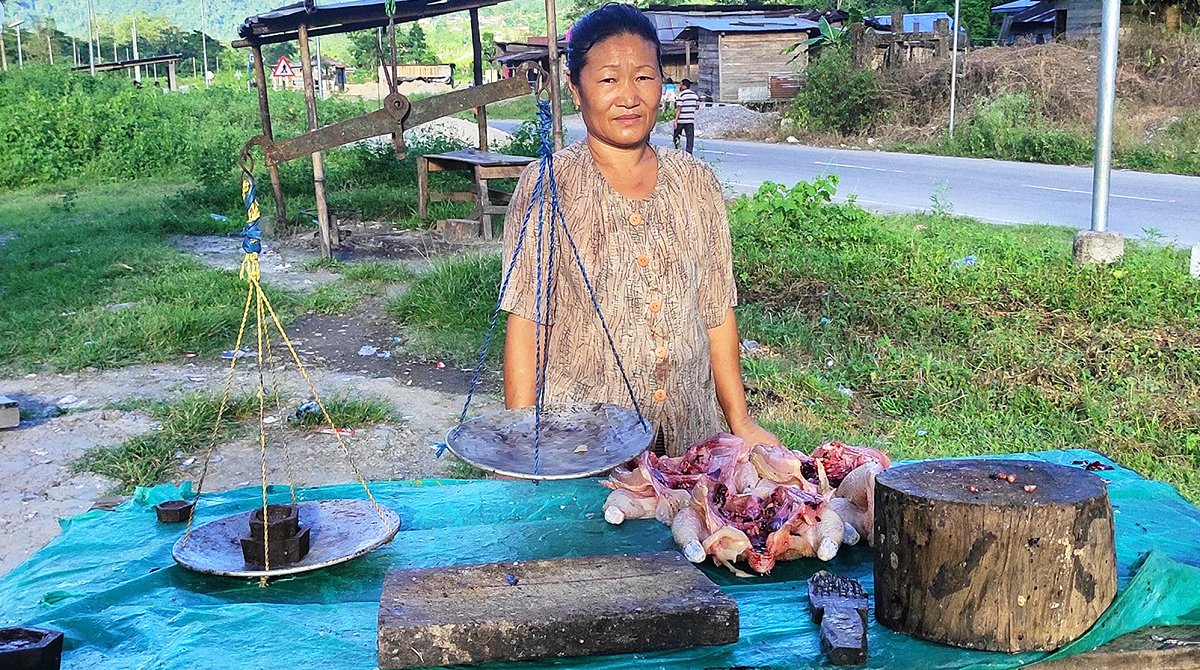 Indien: Eine Frau steht an einem Tisch mit einer Waage und Fleisch