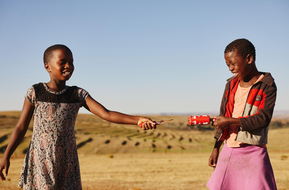 Lesotho: Zwei Kinder ziehen an einem Christmas Cracker.