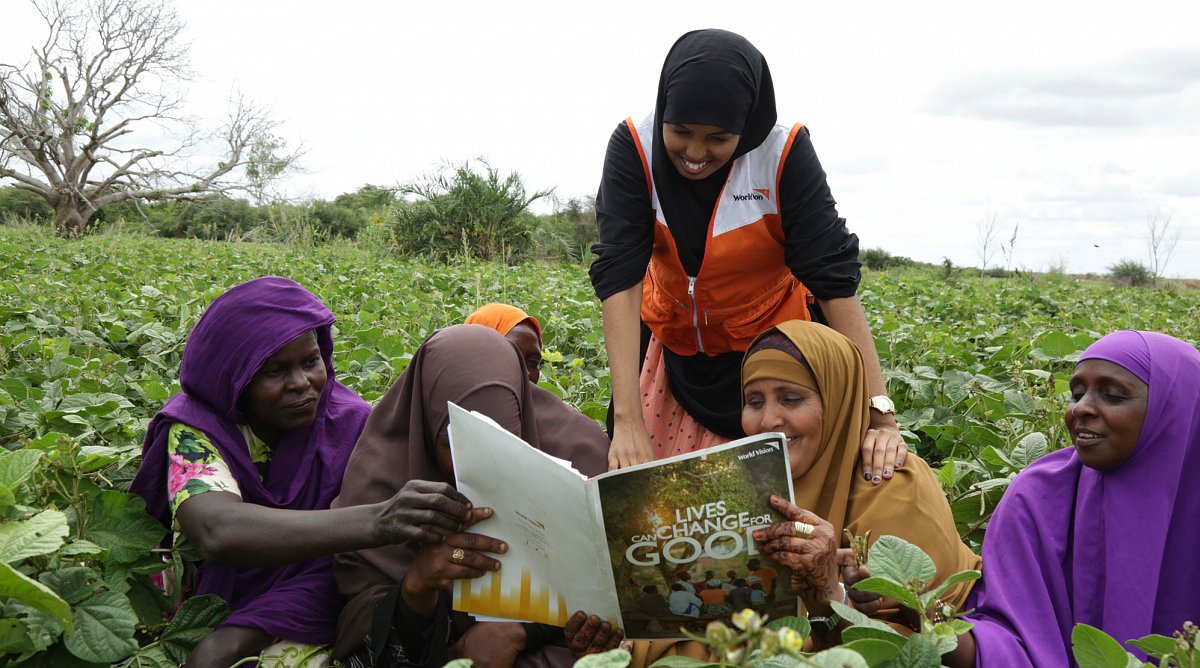 Frauen auf Gemüsefeld in Kenia lesen eine Broschüre