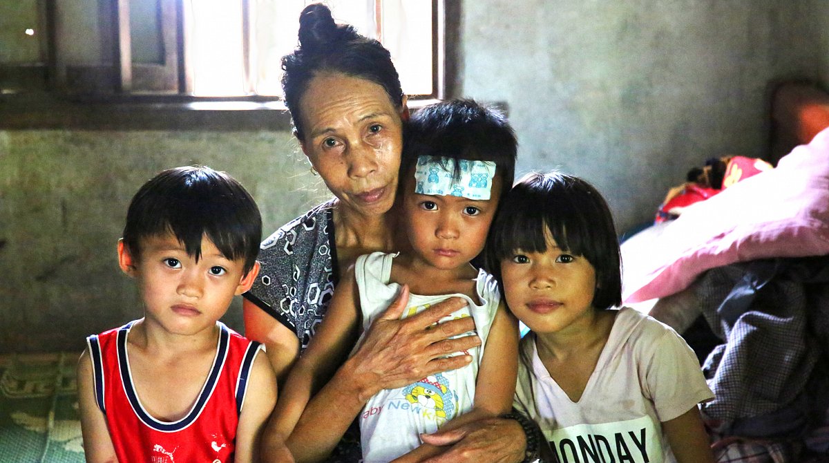 Vietnam: Drei Kinder und ihre Grossmutter sitzen in einem heruntergekommenen Zimmer.