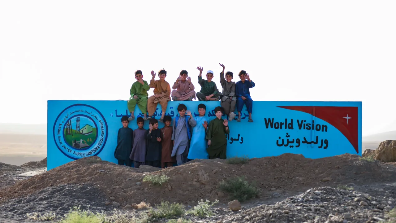 Kinder in Afghanistan stehen vor der Mauer zum neuen Wassersystem