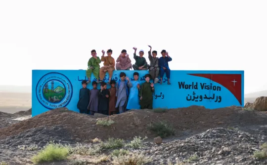 Kinder in Afghanistan stehen vor der Mauer zum neuen Wassersystem