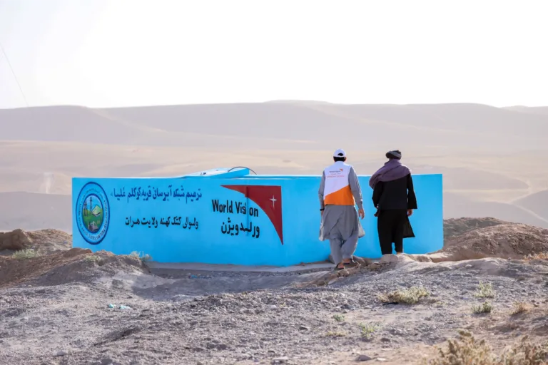 Zwei Männer gehen zu einem neu errichteten Wassersystem in Afghanistan