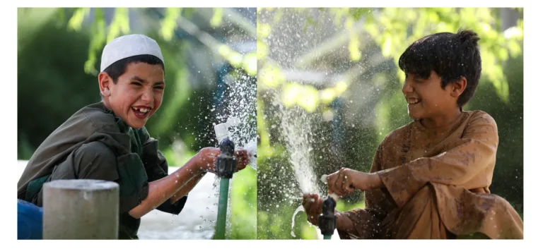 Buben in Afghanistan spritzen Wasser aus den neuen Wasserhähnen.