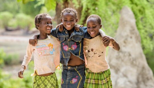 Drei Mädchen aus Sambia spielen gemeinsam