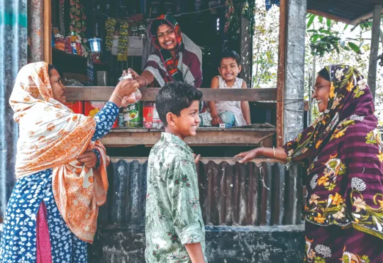Eine Familie kauft im World Vision-Entwicklungsprojekt Muktagacha in Bangladesch an einem Kiosk Eier in einer fröhlichen Stimmung.