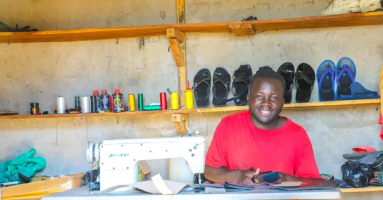 Isaac ist durch das Patenschaftsprogramm von World Vision in Uganda aus der Armut heraus zu einem Schuhmacher geworden. Hier schneidet er Leder zu.