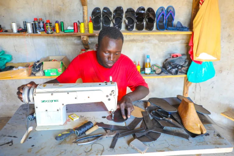 Isaac ist durch das Patenschaftsprogramm von World Vision in Uganda aus der Armut heraus zu einem Schuhmacher geworden. Hier näht er eine Sohle.