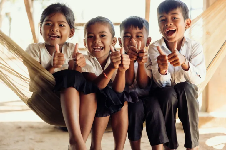 Quatre enfants au Cambodge lèvent le pouce.