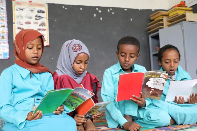 Vier Schulkinder in Äthiopien lesen in Geschichtenbüchern von World Vision.