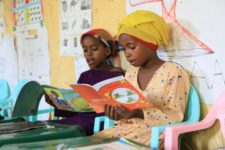 Zwei Mädchen in Aethiopien lesen in Gechichtenbüchern von World Vision.